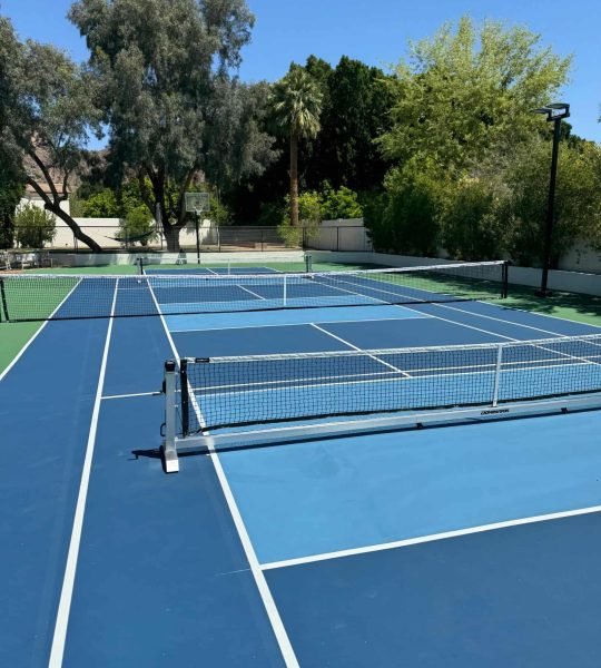 Bright blue tennis court surface with freshly painted white lines and net for optimal play.
