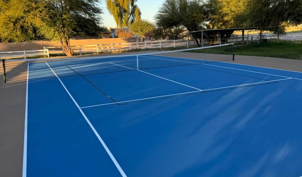 High-quality blue tennis court surface with freshly painted white lines.